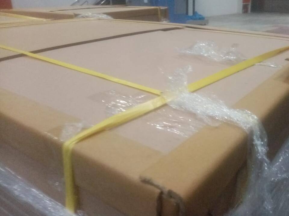Long flat cartons wrapped in film and bound with yellow strapping