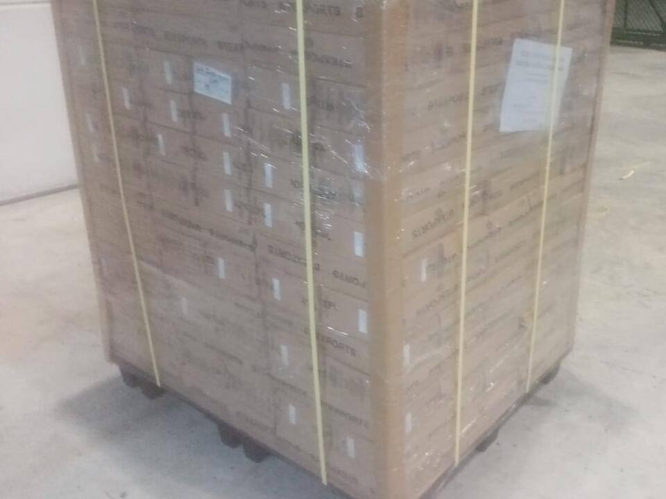 A wrapped and strapped pallet of cartons standing on a warehouse floor
