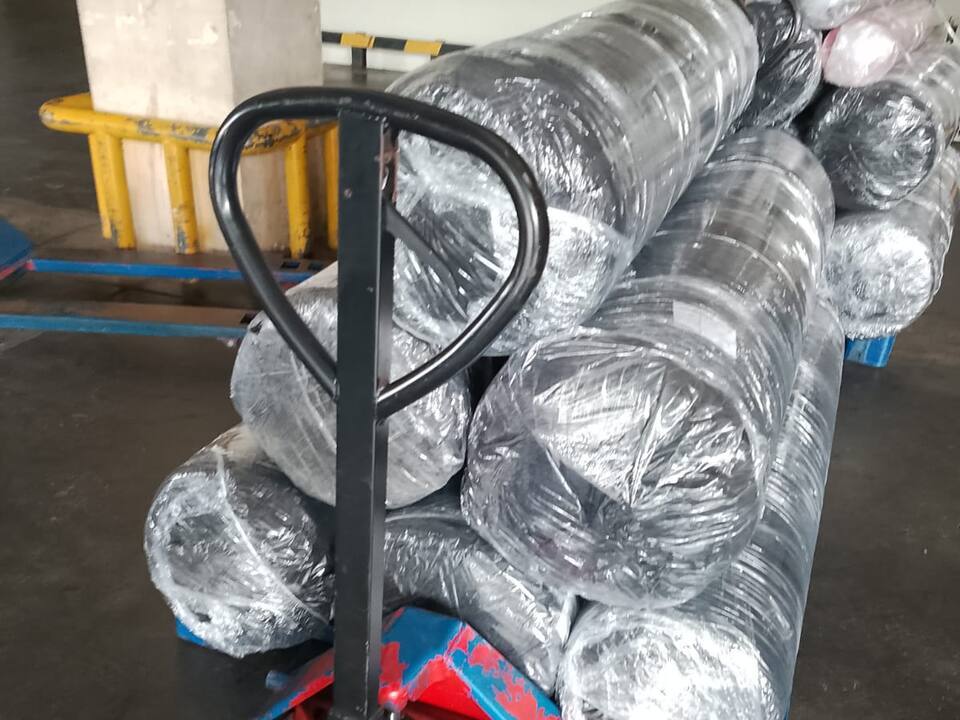Wrapped rolls stacked on a pallet with a hand pallet jack in front