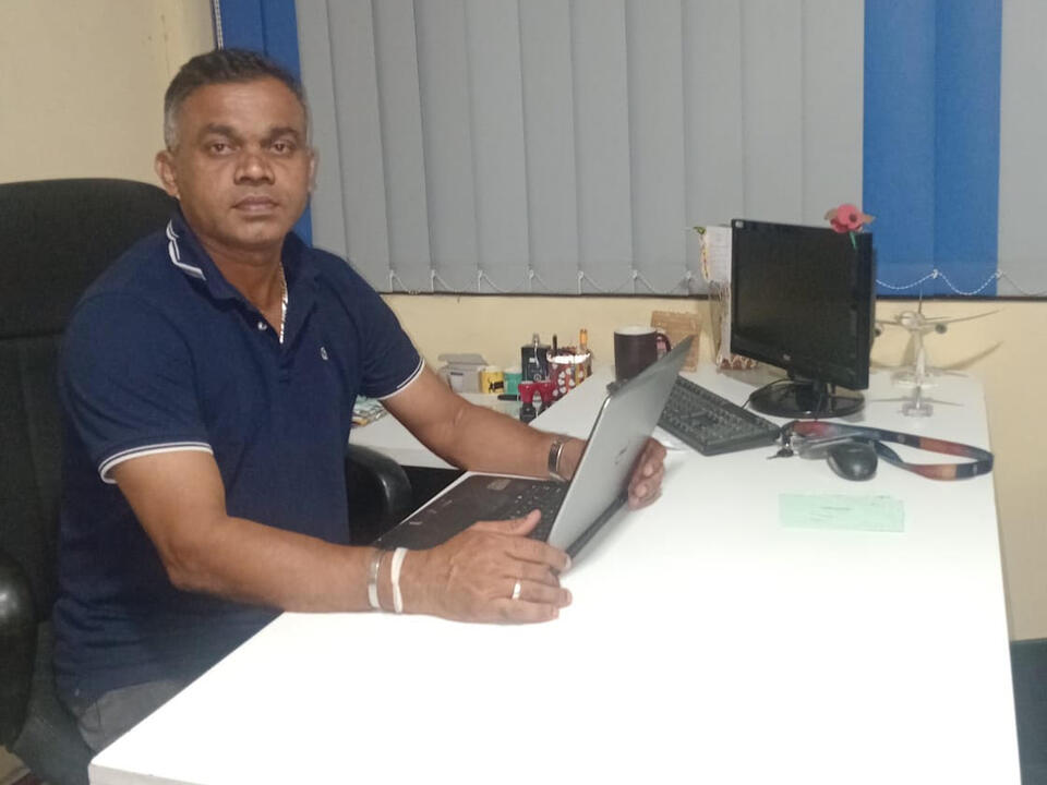 Dinesh Pushpa Kumara, owner of SS Air Cargo, at his desk with a laptop